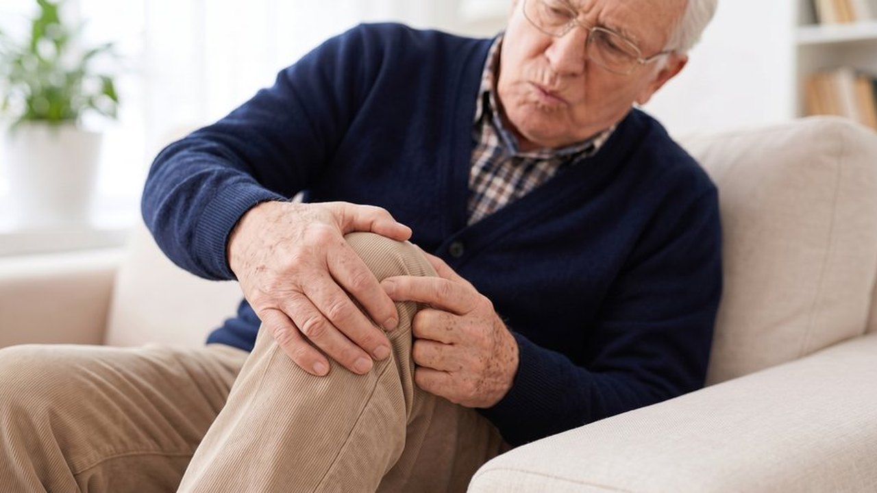 Älterer Mann hält sein schmerzendes Knie.